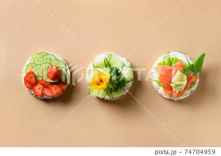 Rice cakes with different types garnish fruits, vegetables, microgreens on natural beige background. Banner. Rice cakes with different types garnish fruits, vegetables, microgreens on natural beige background. Banner. 74704959