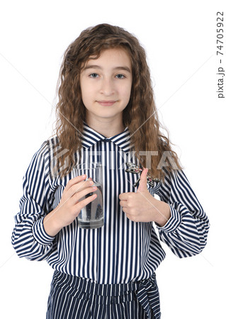 Beautiful young girl holding a glass of clean mineral water in her hand Beautiful young girl holding a glass of clean mineral water in her hand 74705922