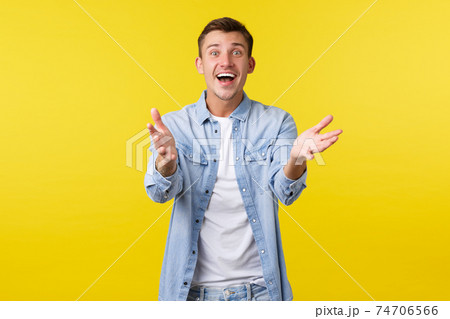 Happy excited handsome man reaching hands forward and smiling amazed, want hold or take something precious, glad to hear fantastic awesome news, receive gift, sanding yellow background 74706566