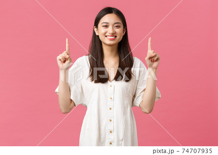 Beauty, people emotions and summer leisure and vacation concept. Cheerful pleased female customer recommend shop, pointing fingers up and smiling delighted, standing pink background 74707935