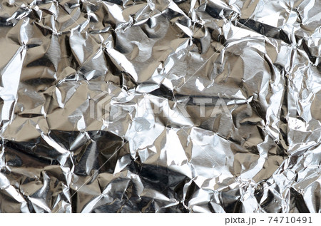 Thin wrinkled sheet of crushed tin aluminum silver foil background with shiny crumpled surface for texture 74710491