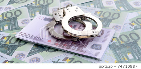 Police handcuffs lies on a set of green monetary denominations of 100 euros. A lot of money forms an infinite heap 74710987