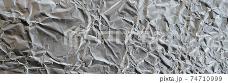 Thin wrinkled sheet of crushed tin aluminum silver foil background with shiny crumpled surface for texture 74710999