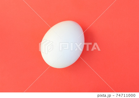 One white egg on a bright red background 74711000
