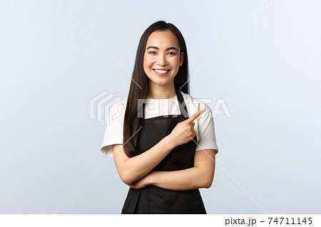 Coffee shop, small business and startup concept. Cheerful asian girl in apron working restaurant or cafe, inviting consumers for special offer. Smiling female staff pointing finger right Coffee shop, small business and startup concept. Cheerful asian girl in apron working restaurant or cafe, inviting consumers for special offer. Smiling female staff pointing finger right 74711145