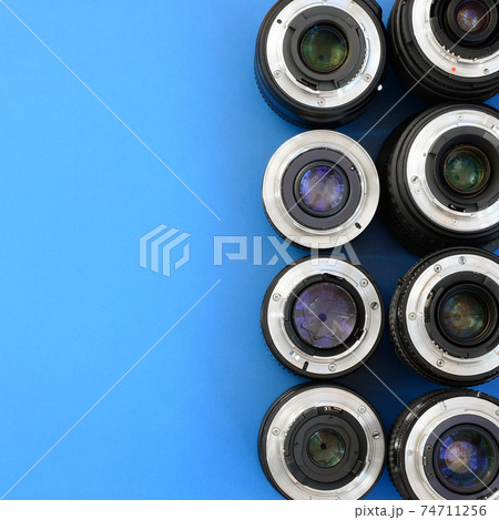 Several photographic lenses lie on a bright blue background. Space for text 74711256