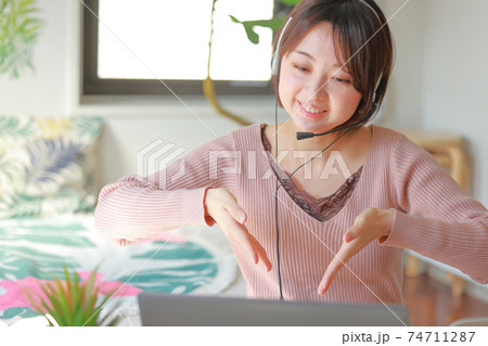 オンラインミーティング_こうやって入れて_と笑顔で説明する女性 オンラインミーティング_こうやって入れて_と笑顔で説明する女性 74711287