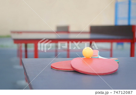 rackets and ball on Ping pong table in outdoor sport yard. Active sports and physical training concept 74712087