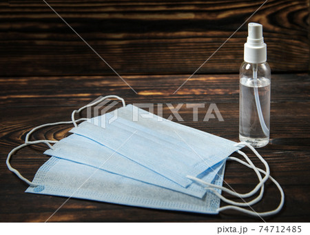 bottle of disinfectant liquid and three medical masks on a wooden table bottle of disinfectant liquid and three medical masks on a wooden table 74712485