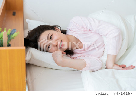 パジャマを着た女性 ベッド 笑顔 パジャマを着た女性 ベッド 笑顔 74714167