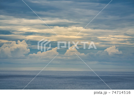 Blue sky with white cumulus clouds above the sea. The sea is a bit hazy. 74714516