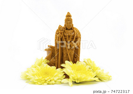 The wooden statue of Lord Murugan with yellow flowers is isolated on a white background The wooden statue of Lord Murugan with yellow flowers is isolated on a white background 74722317