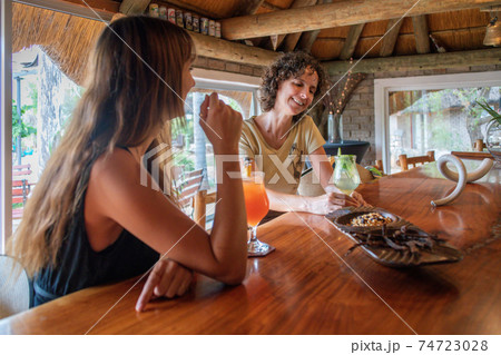 Two smiling brunettes sit drinking in bar Two smiling brunettes sit drinking in bar 74723028