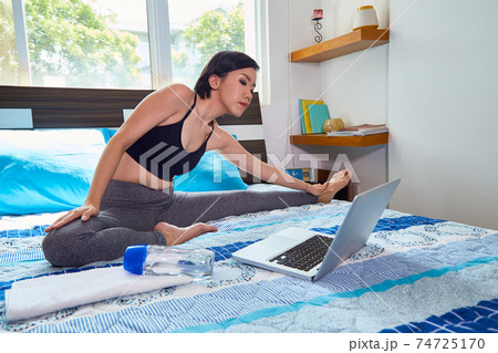 Fit woman stretching on bed 74725170