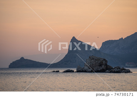 Sea coast with rocky cliffs. Seashore near a mountain with rocks and small waves. 74730171