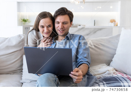 Cheerful couple looking at screen of laptop 74730658