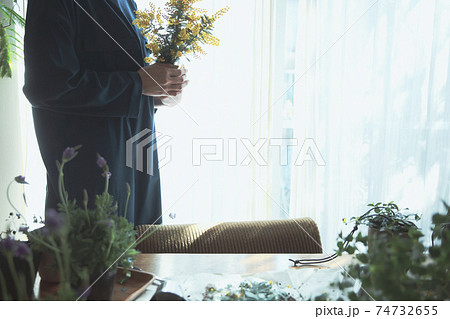 黄色の花のミモザを持つ女性 74732655