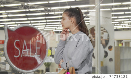 Young woman looking at the display of a store at the mall Young woman looking at the display of a store at the mall 74733121