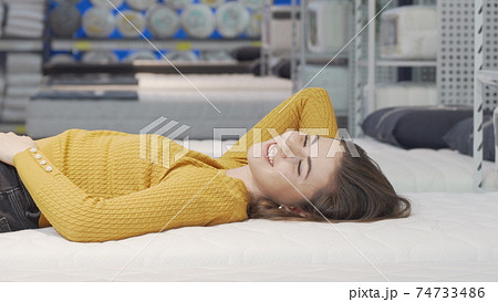 Happy young woman enjoying lying on new mattress at furniture store Happy young woman enjoying lying on new mattress at furniture store 74733486