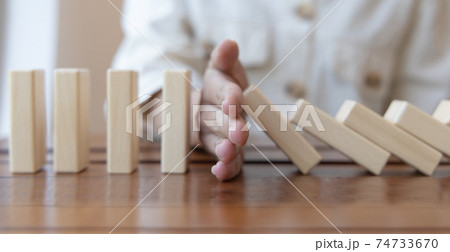 Businesswoman stops hands falling over domino to stop risk continuously, Continuous damage reduction, Stop business domino failures concept. 74733670