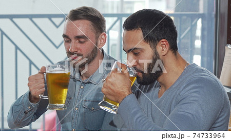 Happy male friends clinking beer glasses enjoying drinking at the pub Happy male friends clinking beer glasses enjoying drinking at the pub 74733964
