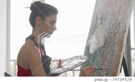 Young elegant woman painting at her workshop Young elegant woman painting at her workshop 74734529