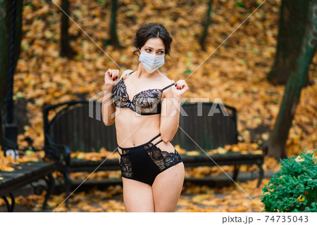 Fashion portrait of sexy woman in face mask and bodysuit in autumn park. Pandemic, coronavirus Fashion portrait of sexy woman in face mask and bodysuit in autumn park. Pandemic, coronavirus 74735043