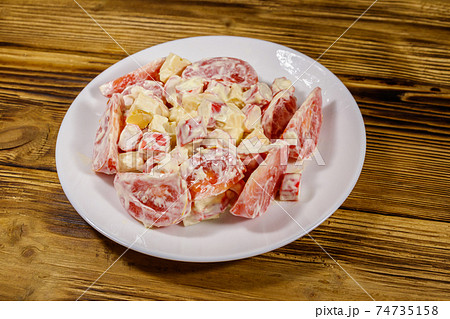 Tasty salad with crab sticks, cheese, tomato and mayonnaise on wooden table 74735158