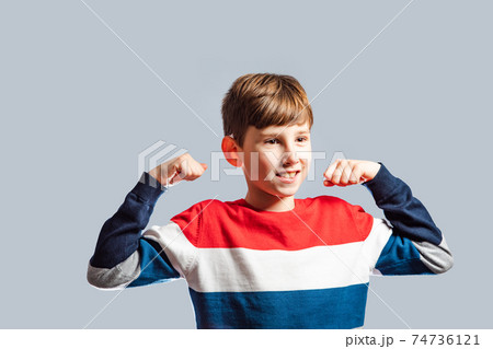 the smiling boy with raised hands demonstrates his muscular 74736121