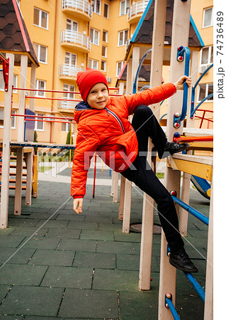 Boy strengthens his body climbing on outdoor playground 74736489