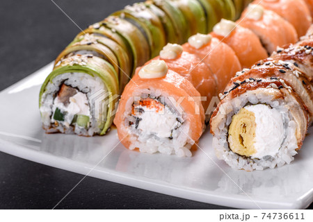 Fresh tasty sushi rolls laid out in the form of a dragon with ginger and wasabi Fresh tasty sushi rolls laid out in the form of a dragon with ginger and wasabi 74736611