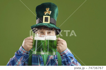 Happy guy celebrating Saint Patrick's Day and enjoying green beer from two big glasses Happy guy celebrating Saint Patrick's Day and enjoying green beer from two big glasses 74736767