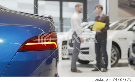 Car dealer shaking hands with male client at automobile dealership 74737376