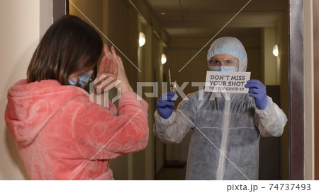 Medical worker with text on paper visiting woman at home offering vaccination against coronavirus 74737493