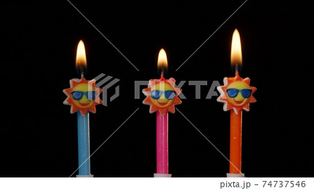 Birthday festive candles in form of sun in sunglasses isolated on black background 74737546