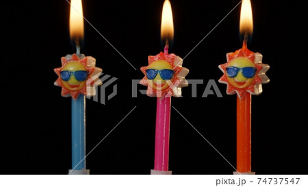 Birthday festive candles in form of sun in sunglasses isolated on black background 74737547