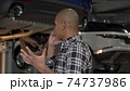Stressed young man talking on the phone at the garage 74737986
