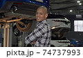 Cheerful African man smiling to the camera standing at cars workshop 74737993