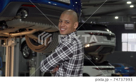 Cheerful African man smiling to the camera standing at cars workshop 74737993