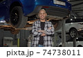 Happy handsome car repairman smiling to the camera at his garage 74738011