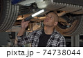 Young African man examining his automobile at the workshop 74738044