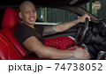 Happy handsome African man smiling to the camera sitting in his sports car 74738052