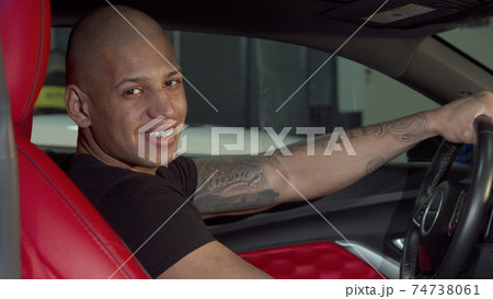 Cheerful handsome African man smiling to the camera while sitting in his car 74738061