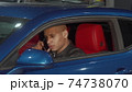 Handsome young man talking on the phone sitting in his car 74738070