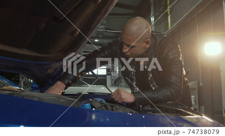 Young handsome man repairing his car at the garage Young handsome man repairing his car at the garage 74738079
