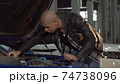 Young African man examining engine of his car at the garage 74738096
