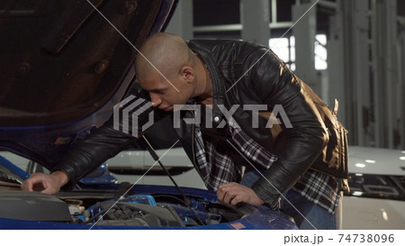 Young African man examining engine of his car at the garage Young African man examining engine of his car at the garage 74738096