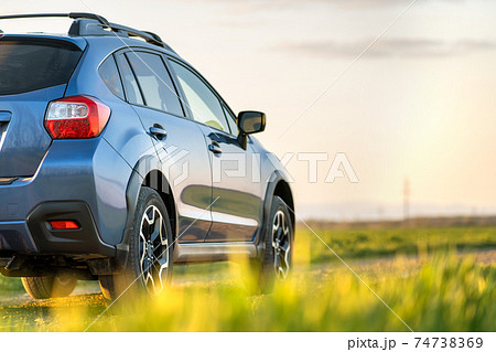 Landscape with blue off road car on gravel road. Traveling by auto, adventure in wildlife, expedition or extreme travel on a SUV automobile. Offroad 4x4 vehicle in field at sunrise. 74738369