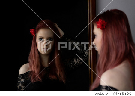 Young woman in flamenco clothes is looking at herself in the mirror. 74739350
