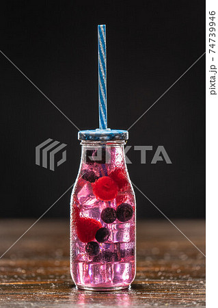 Pink cocktail in a high glass decorated with orange, raspberries, strawberries and blueberries Pink cocktail in a high glass decorated with orange, raspberries, strawberries and blueberries 74739946
